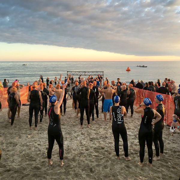 A group of people standing on the beach waiting for the race to begin.