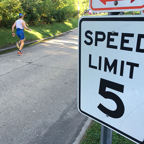 A person running past a speed limit sign.