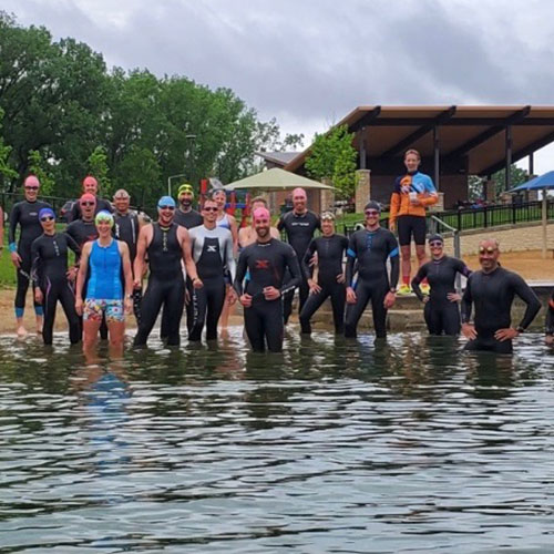 A group of people in wetsuits standing outside in the water.